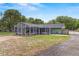 Wide backyard shot featuring a screened-in patio, lush lawn, and a serene outdoor setting at 39812 French Rd, Lady Lake, FL 32159