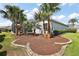 Beautifully landscaped backyard featuring palm trees, lush shrubbery, and a charming exterior at 4033 Swaying Palm Ct, The Villages, FL 32163