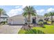 Inviting single-story home with a well-kept lawn, beautiful landscaping with palm trees, and a convenient two-car garage at 4033 Swaying Palm Ct, The Villages, FL 32163