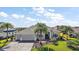 Attractive single-story home boasting lush landscaping, mature palm trees, and a wide driveway leading to a two-car garage at 4033 Swaying Palm Ct, The Villages, FL 32163