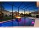 Screened-in pool with a fire feature and a view of the backyard at twilight at 4033 Swaying Palm Ct, The Villages, FL 32163
