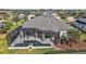 Aerial view of a screened-in pool area with patio furniture, adjacent to a well-maintained backyard at 4033 Swaying Palm Ct, The Villages, FL 32163