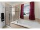 Bright bathroom boasts tiled walls, a glass shower, soaking tub beneath a window with privacy curtains at 422 Rock Springs Cir, Groveland, FL 34736