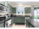 Updated kitchen with stainless steel appliances, dark countertops, tile floors, dark green cabinets, and natural light from a window at 422 Rock Springs Cir, Groveland, FL 34736