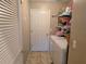 Functional laundry room with washer, dryer, shelving, and neutral tile flooring at 5300 Treasure View Way, Leesburg, FL 34748