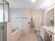 Bathroom featuring a tiled tub and separate vanity with a large mirror and ample lighting at 5324 Treasure View Way, Leesburg, FL 34748