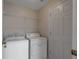 Laundry room with a white washer and dryer, door and wire rack shelving at 5324 Treasure View Way, Leesburg, FL 34748