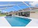 Sparkling screened-in pool with solar panels on the roof and outdoor seating area at 5400 Saddleback Ct, Lady Lake, FL 32159