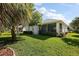 Exterior view of the home showing the enclosed patio, lush lawn, mature landscaping, and well-maintained yard at 5604 Gulf Stream St, Tavares, FL 32778