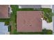 Aerial view of a well-maintained brown roof, green lawn, landscape, and neighboring properties at 627 Leeds Pl, The Villages, FL 32162