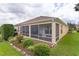 Exterior view of a home with a screened porch and beautifully landscaped backyard at 627 Leeds Pl, The Villages, FL 32162