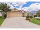 Attractive single-story home featuring a manicured front lawn, a two-car garage and a neatly maintained landscape at 627 Leeds Pl, The Villages, FL 32162