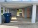 Carport with concrete floor, supporting posts, trash can, and a laundry room at 640 Mansfield Rd, Tavares, FL 32778