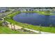 Scenic aerial view of a peaceful community lake with walking paths, lush green spaces, and charming neighborhood homes at 6488 Barnstorm Way, St Cloud, FL 34771