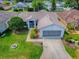 Aerial view of a charming home with well-manicured lawn, mature landscaping, and a two-car garage at 712 Old Oaks Ln, Leesburg, FL 34748
