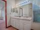 Bathroom features double sinks, a large mirror, and a window for natural light and ventilation at 712 Old Oaks Ln, Leesburg, FL 34748