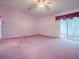 Spacious bedroom featuring plush pink carpeting, a ceiling fan, and sliding glass doors at 712 Old Oaks Ln, Leesburg, FL 34748