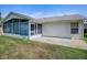 Rear exterior featuring a screened-in porch, a concrete patio, and well-maintained lawn at 712 Old Oaks Ln, Leesburg, FL 34748