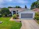 Charming home featuring a well-maintained lawn, mature landscaping, and a two-car garage at 712 Old Oaks Ln, Leesburg, FL 34748