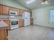 Well-lit kitchen featuring white appliances, wood cabinets, and a ceiling fan with decorative light fixture at 712 Old Oaks Ln, Leesburg, FL 34748