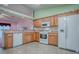 Bright kitchen features wood cabinets, white appliances, and a breakfast bar that opens to an adjacent room at 712 Old Oaks Ln, Leesburg, FL 34748