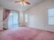 Bright bedroom featuring a ceiling fan and sliding glass door to a screened lanai at 712 Old Oaks Ln, Leesburg, FL 34748