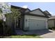 Two-car garage in a blue home with gray stone accents, green grass, and a well manicured tree at 7955 Delwin Ln, Reunion, FL 34747
