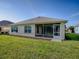 A screened in lanai sits off the back of this home with a lush green lawn at 8601 Se 133Rd St, Summerfield, FL 34491