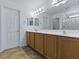 Bathroom with double vanity, tiled floor, framed mirrors, and a glass-enclosed shower at 8601 Se 133Rd St, Summerfield, FL 34491
