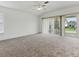 Spacious bedroom with neutral carpet, ceiling fan, window, and sliding glass doors leading to the backyard at 8601 Se 133Rd St, Summerfield, FL 34491