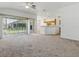 Open-concept living room features neutral carpet, sliding glass doors, and a view of the kitchen at 8601 Se 133Rd St, Summerfield, FL 34491