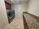 Well-equipped laundry room with modern washer and dryer, granite countertops, and ample cabinet space at 8719 Kenmure Cv, Orlando, FL 32836