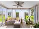 Screened-in patio with woven sofa, striped curtains, ceiling fan, and plants at 965 Eastmont Ct, The Villages, FL 32162