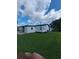 Back exterior view of home, with green lawn, a carport on the left and an air conditioning unit on the right at 1005 Matthew Ave, Lady Lake, FL 32159