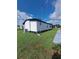 Exterior side view of home showing the lawn, air conditioning unit and a narrow sidewalk at 1005 Matthew Ave, Lady Lake, FL 32159