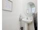 Stylish bathroom with pedestal sink, round mirror, and elegant decor at 1042 Lido Dr, Howey In The Hills, FL 34737