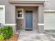 Inviting covered front porch with blue door, neutral paint, and landscaped flower bed at 1042 Lido Dr, Howey In The Hills, FL 34737