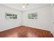 This bedroom features rich wood floors, white walls, two windows, and a ceiling fan at 11214 Sw 77Th Ct, Ocala, FL 34476