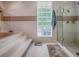 Bathroom featuring a soaking tub with tile surround, glass block window and separate glass shower at 11226 Lane Park Rd, Tavares, FL 32778