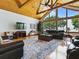 Open living room with wood floors, vaulted ceiling, large windows overlooking the lake, and a comfortable leather seating at 11226 Lane Park Rd, Tavares, FL 32778