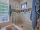 Spacious walk-in shower with glass door, tile surround, glass block window and built-in shelving at 11226 Lane Park Rd, Tavares, FL 32778