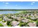 An aerial view displays neighborhood homes near a lake, enhanced by lush landscaping and blue skies at 1123 Barnacle Ter, The Villages, FL 32162