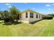 Well-maintained backyard showcasing the home's exterior, featuring a screened-in lanai, lush lawn, and mature landscaping at 1123 Barnacle Ter, The Villages, FL 32162