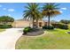 Charming one-story home featuring a well-manicured lawn, mature palm trees, and an attached two-car garage at 1123 Barnacle Ter, The Villages, FL 32162