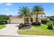 Charming one-story home featuring a well-manicured lawn, mature palm trees, and an attached two-car garage at 1123 Barnacle Ter, The Villages, FL 32162