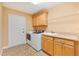 Bright laundry room featuring tile floors, overhead cabinets, white appliances, and a utility sink with vanity at 1123 Barnacle Ter, The Villages, FL 32162