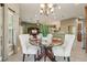 Elegant dining area with a glass table, white chairs, and views of the living spaces at 1304 Zombar Pl, The Villages, FL 32163