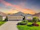 Charming single-story home boasting a three-car garage, lush landscaping, and inviting curb appeal at sunset at 1304 Zombar Pl, The Villages, FL 32163