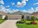 Charming single-story home features a well-manicured lawn, mature landscaping, and a three-car garage at 1304 Zombar Pl, The Villages, FL 32163