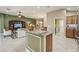 Open-concept living area and kitchen with modern appliances, neutral tones, and eat-in bar at 1304 Zombar Pl, The Villages, FL 32163